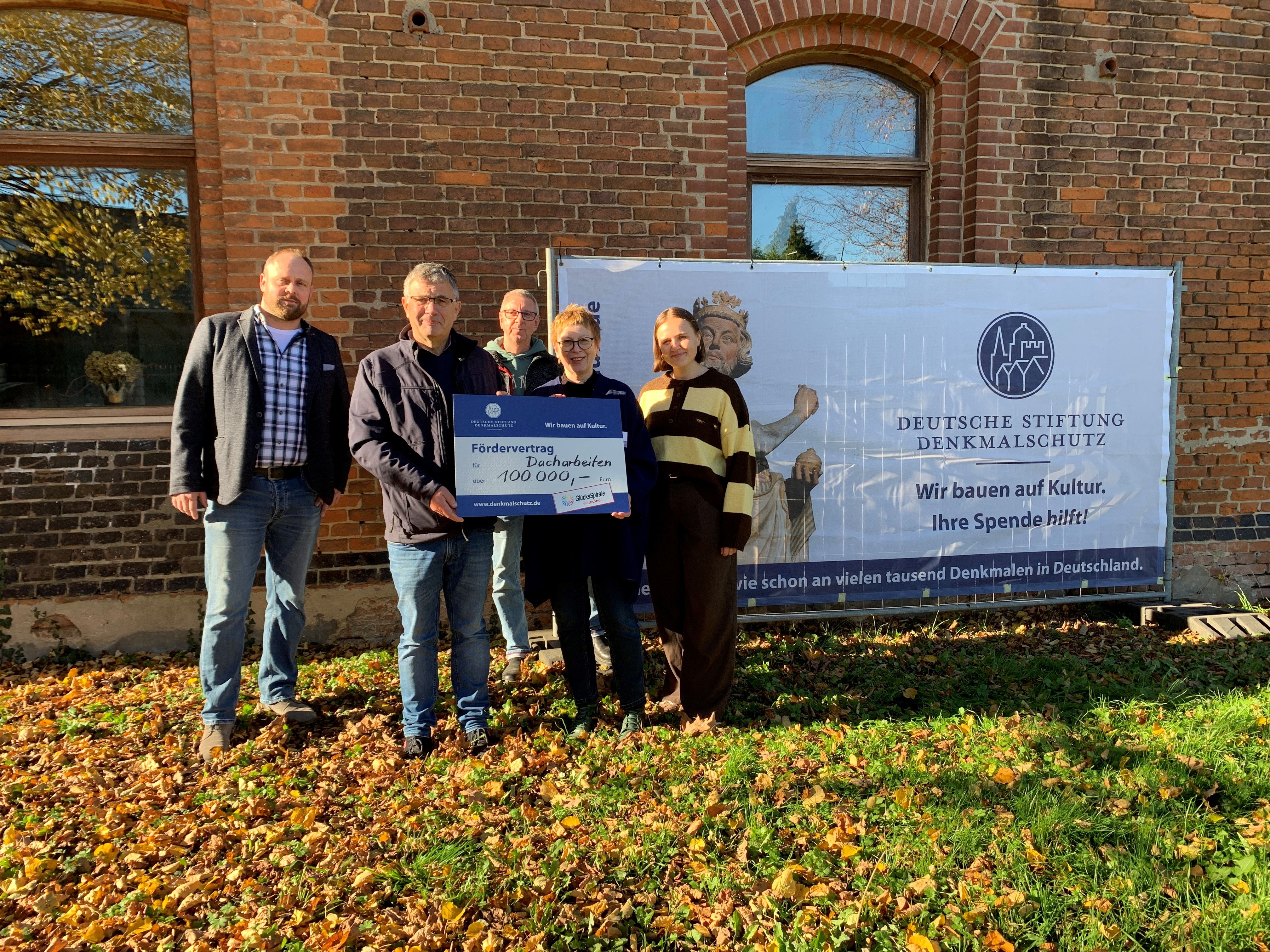 Eine Gruppe Menschen mit Förderscheck vor einem Gebäude