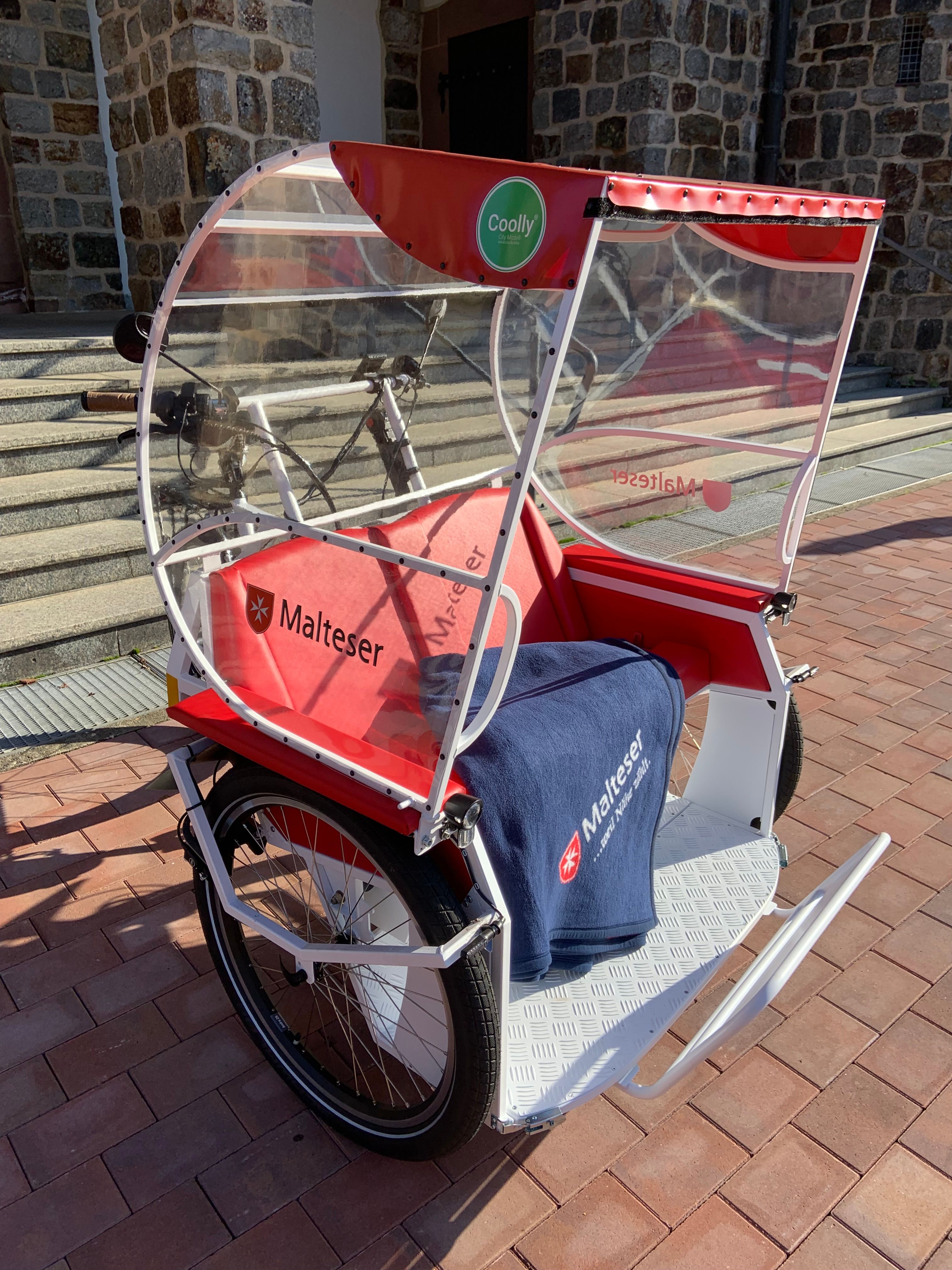 Eine Rikscha mit roten Sitzen und blauer Decke