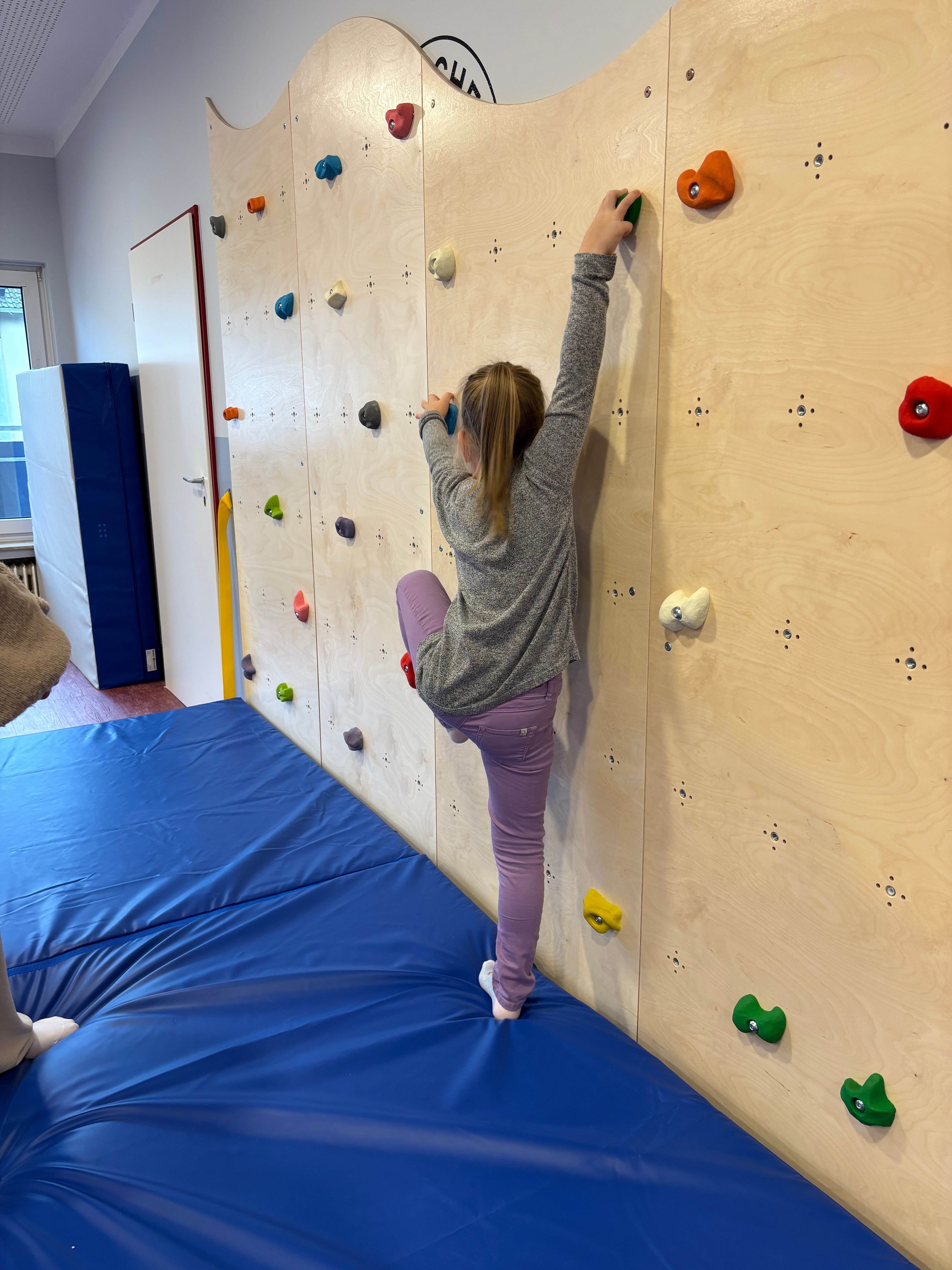 Ein Mädchen klettert an der Kletterwand