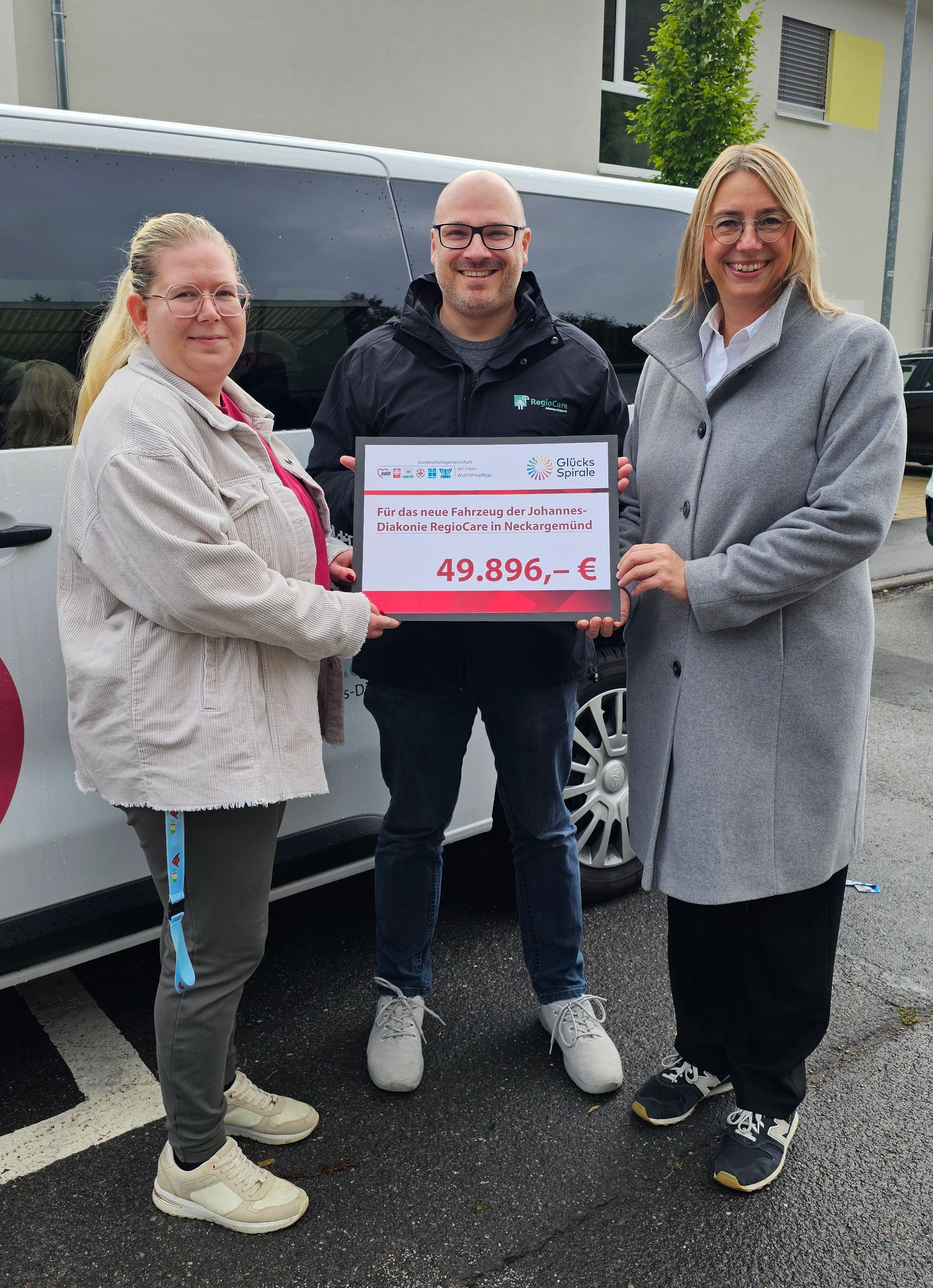 Eine Gruppe Menschen mit Förderscheck vor einem Kleinbus