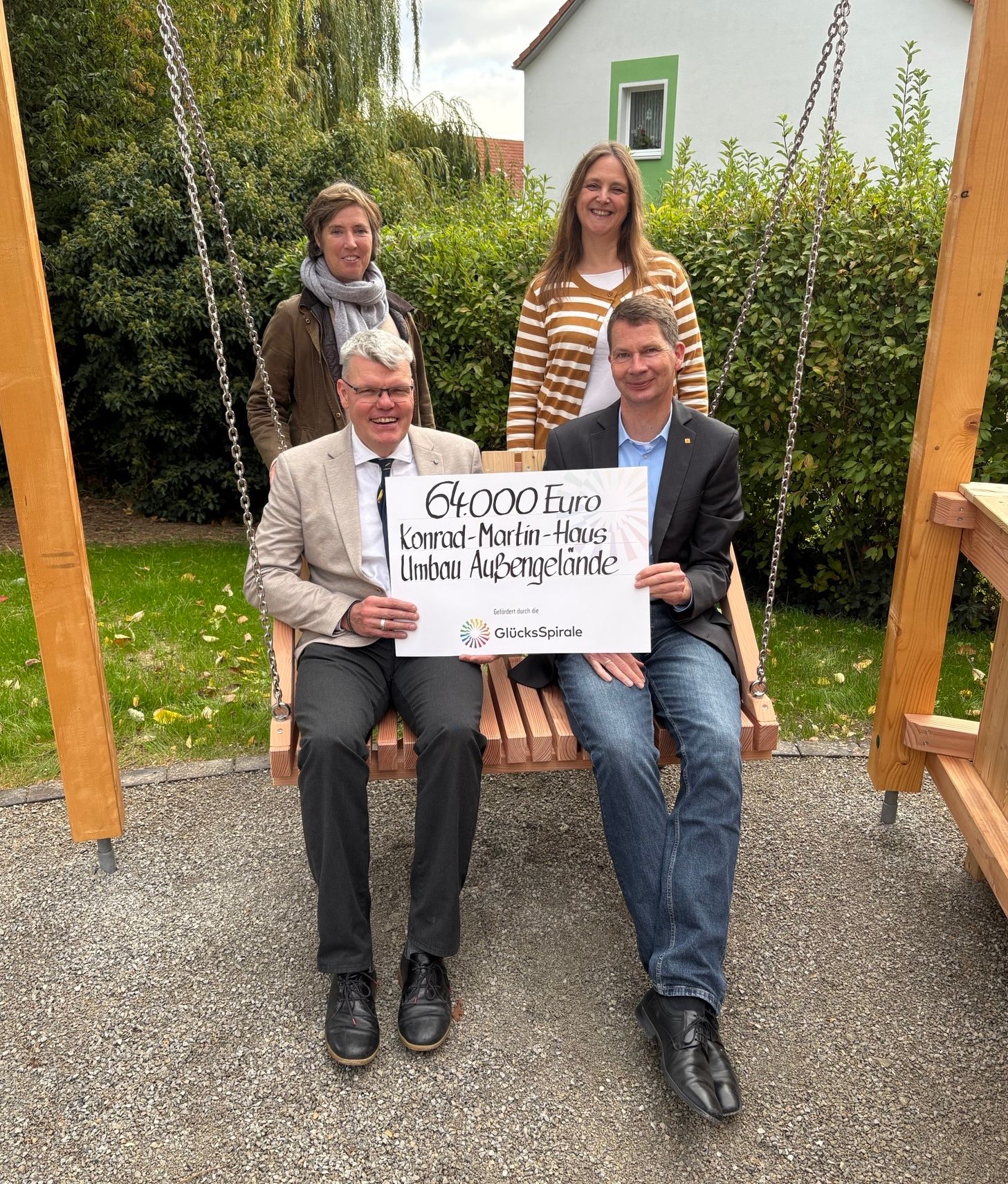 Eine Gruppe Menschen mit Förderscheck auf einer Holz-Schaukel