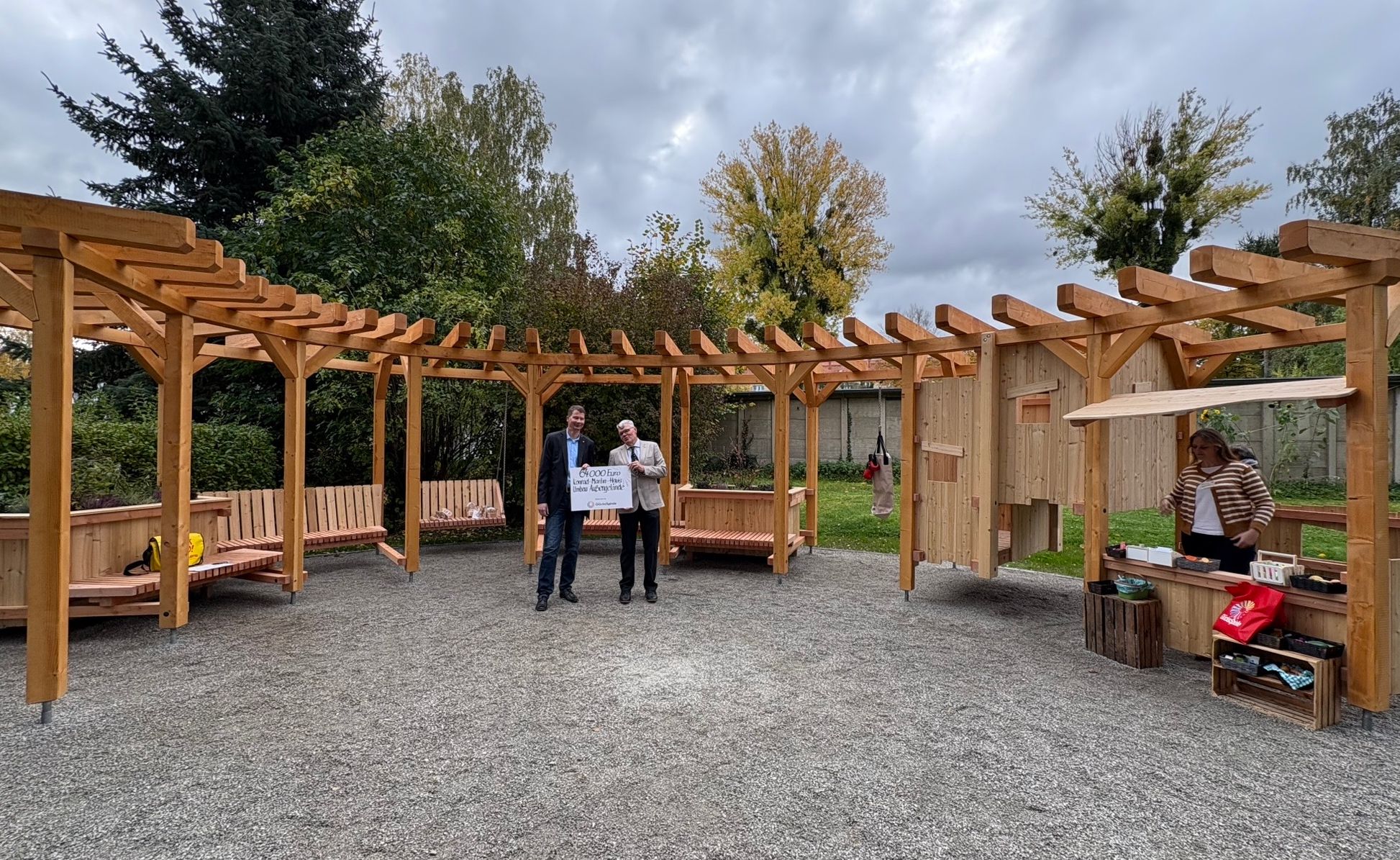 Zwei Männer mit Förderscheck in einem Garten mit Holz-Pergola